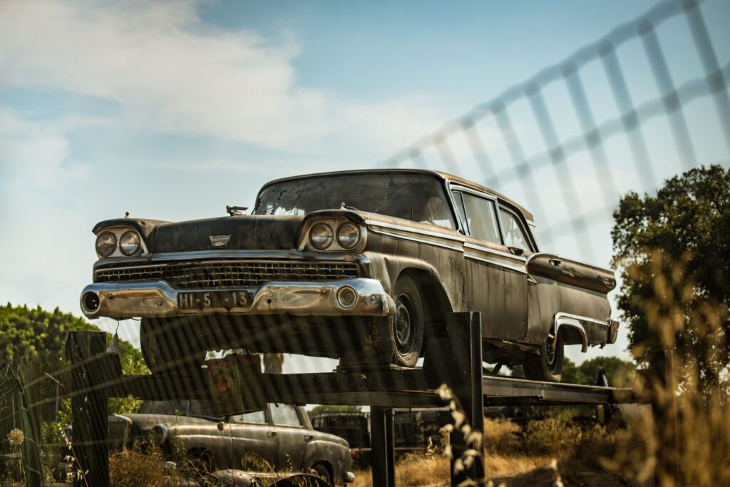 A classic 1950s Ford Fairlane 500 rusting in a Portuguese scrapyard, evoking nostalgic memories.
